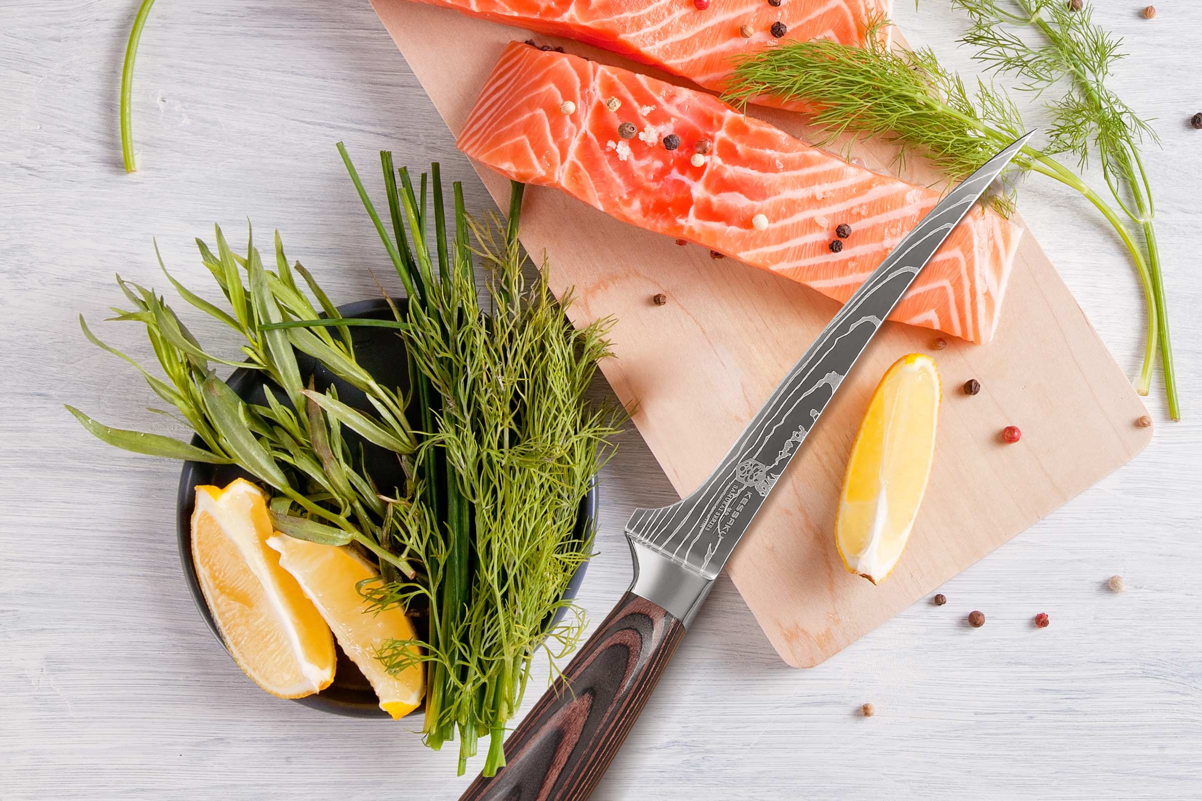 The Samurai Fillet Knife used to to make two salmon steaks. Wedges of lemon, peppercorns, and herbs accompany.