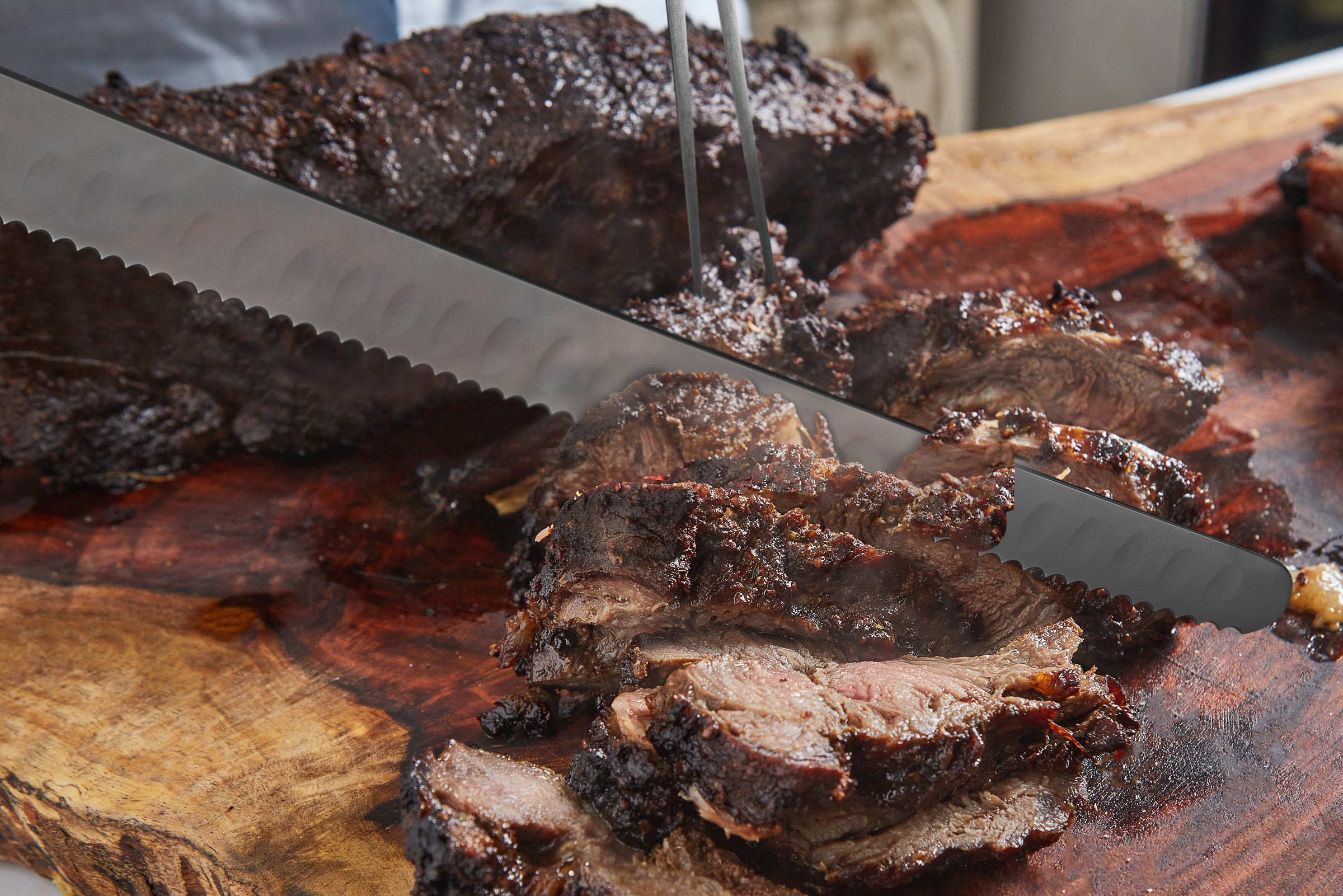 The Samurai Serrated Carving Knife slicing thick cuts of still steaming beef