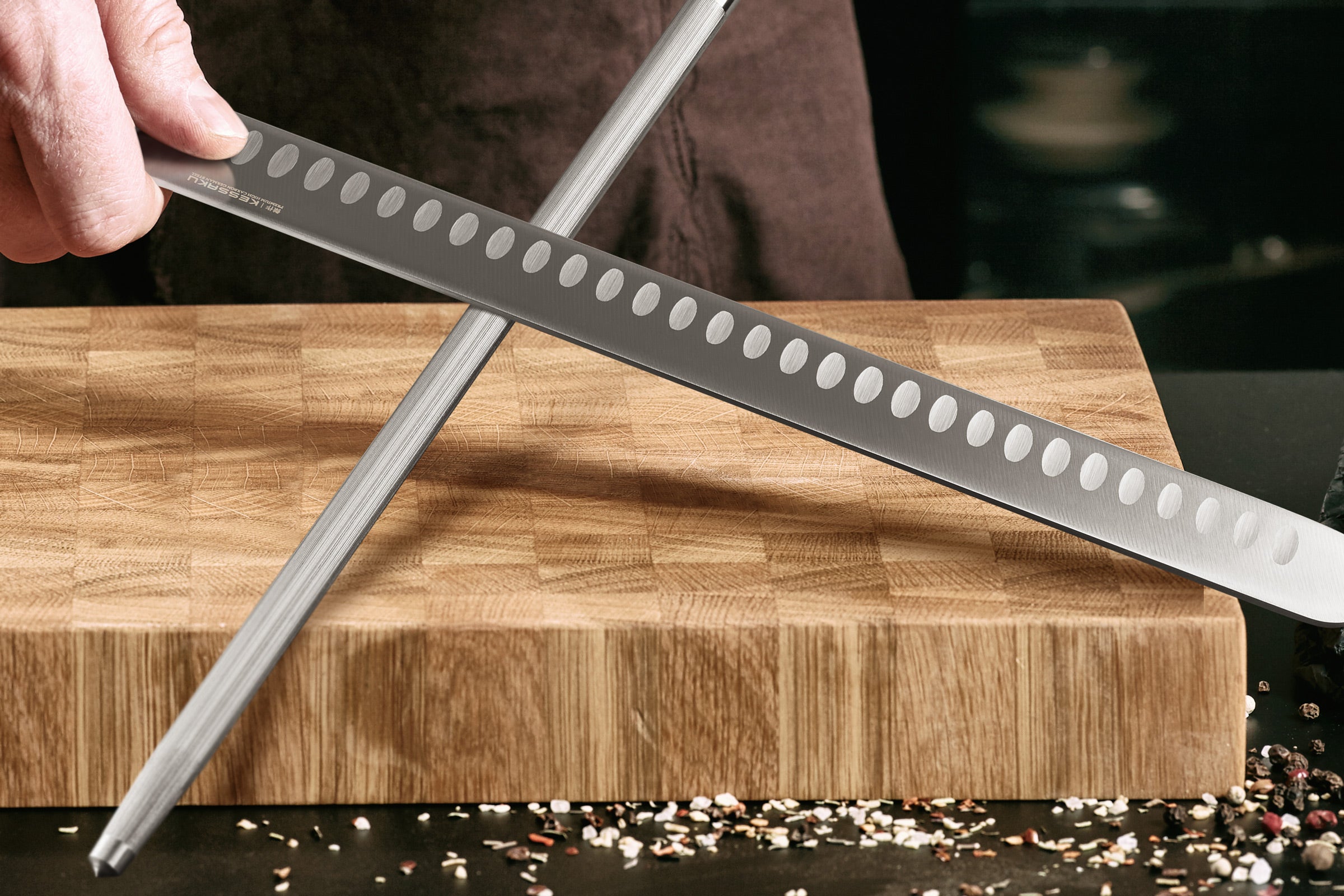 A chef hones the Dynasty Carving Knife with the Dynasty Honing Steel before food preparation.