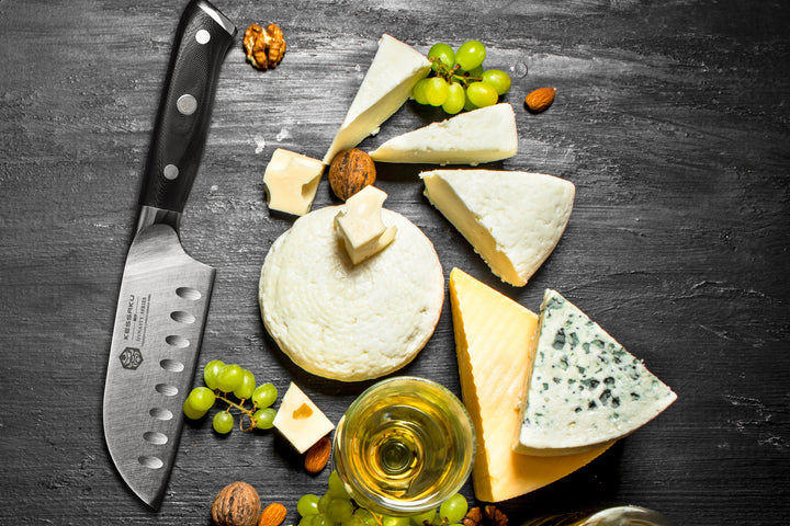 The Dynasty Santoku with an assortment of sliced cheeses, grapes, walnuts, and white wine.