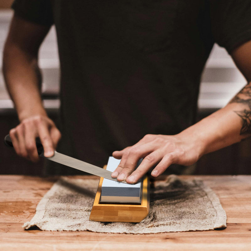 A chef using the Double-Sided Whetstone Kit to sharpen a knife