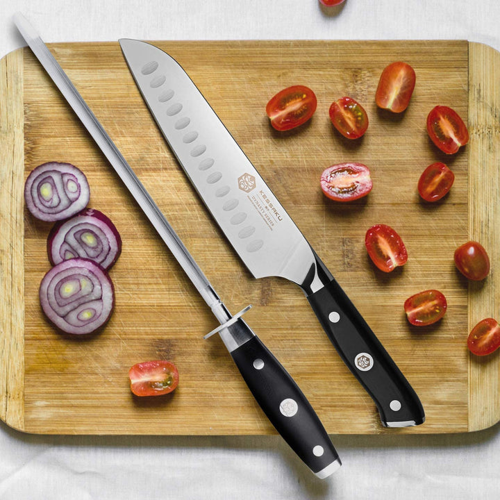 The Dynasty Honing Steel and Santoku on a cutting board with sliced red onions and cherry tomatoes