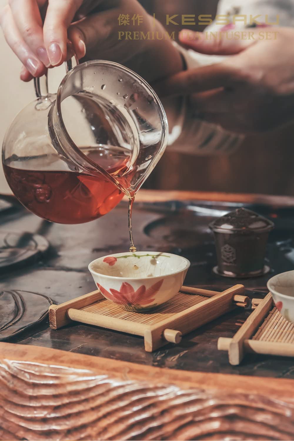 A woman pours freshly steeped tea into a small cup